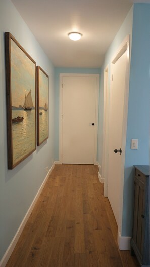 A hallway with wooden flooring, light blue walls, and two doors.