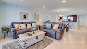 A living room with two sofas, a coffee table, and a kitchen in the background. - Gorgeous Punta Rassa Condo 504 - River and Sunset views! (Fort Myers)