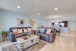 A living room with two sofas, a coffee table, and a kitchen in the background. - Gorgeous Punta Rassa Condo 504 - River and Sunset views! (Fort Myers)