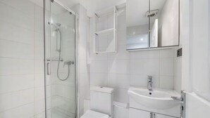 Ein modernes Badezimmer mit einer Duschkabine, einer Toilette und einem Waschbecken mit Spiegel.