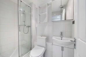 Ein modernes Badezimmer mit einer Duschkabine, einer Toilette und einem Waschbecken mit Spiegel.