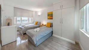 Ein Schlafzimmer mit zwei Betten, einem Kleiderschrank, einem Heizkörper, einem Fenster und einem Bild.