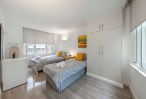 Ein Schlafzimmer mit zwei Betten, einem Kleiderschrank, einem Heizkörper, einem Fenster und einem Bild.
