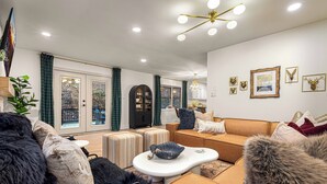 Un salon moderne avec un canapé, des poufs et un lustre.