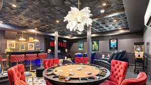 Une salle aménagée comme un casino, avec une table de blackjack, des fauteuils en velours rouge et un plafond orné de motifs de feuilles.
