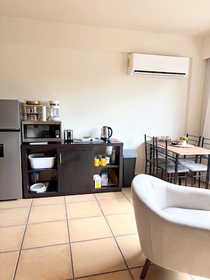 A compact kitchen with a microwave, coffee maker, and kettle, a dining table with chairs, and a trash bin. - Coronado Luxury Club & Suites
with golf for 2 (Provincia de Panamá Oeste)