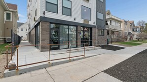 A modern building with a glass facade, a brick entrance, and a metal railing in front. - Valclyde Cozy Suite-Sleeps 4-Downtown-MPLs (Minneapolis)