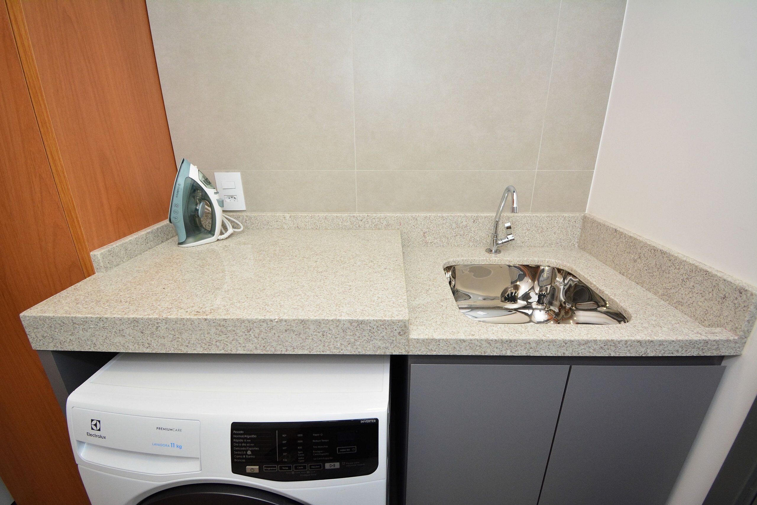 A kitchen with a built-in washing machine, a stainless steel sink, and a countertop.
