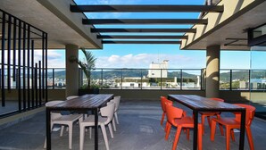 Une terrasse sur le toit avec des sièges extérieurs, une pergola et une vue sur le paysage urbain.