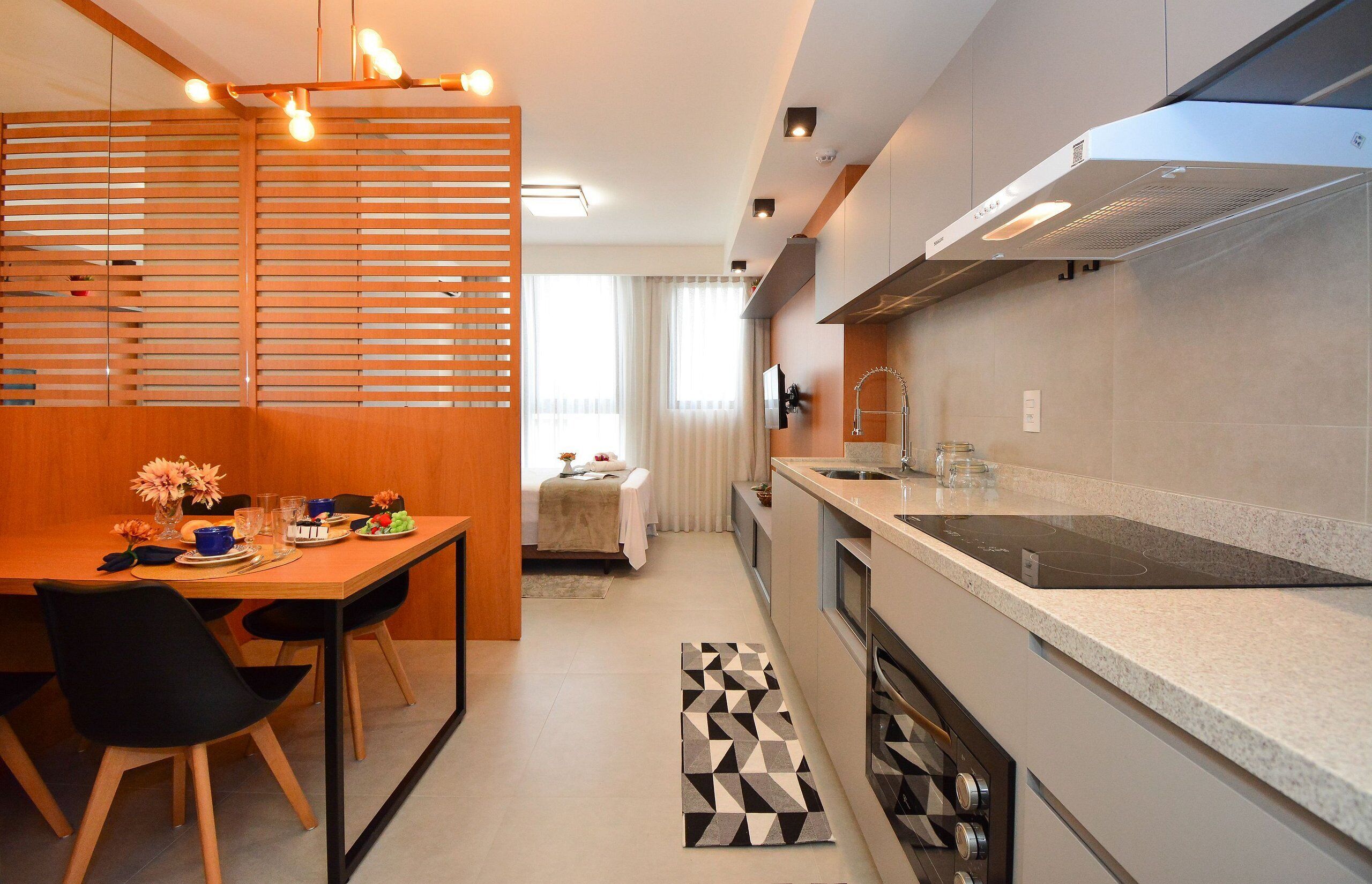 A modern kitchen with a dining area, a built-in stove, and a window with curtains.