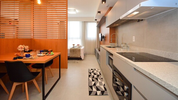 Une cuisine moderne avec un coin repas, une cuisinière intégrée et une fenêtre avec des rideaux.