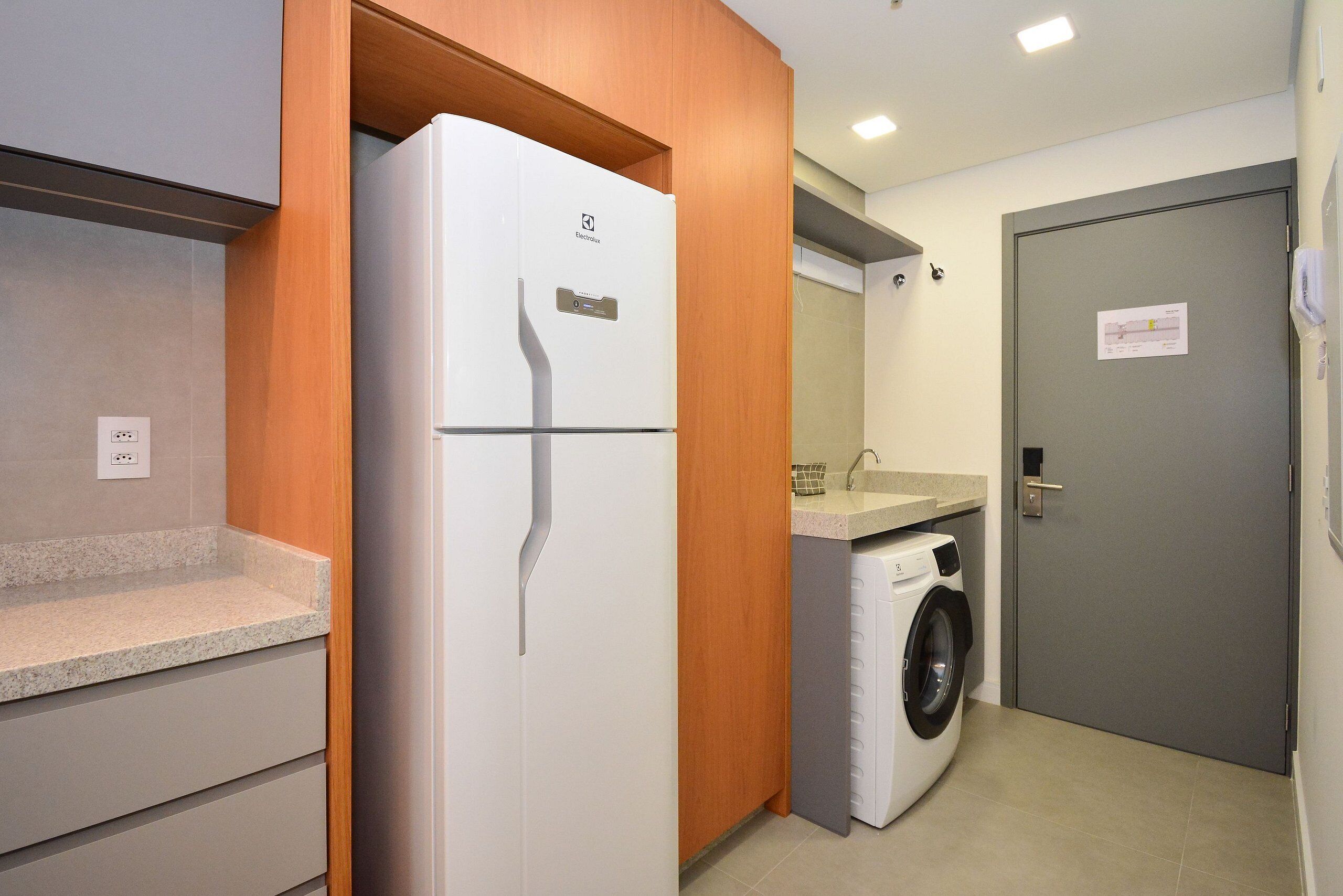 A compact kitchen with a refrigerator, washing machine, and a small countertop.