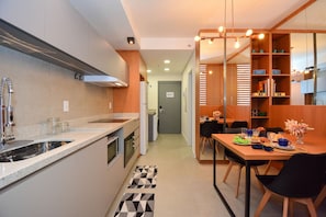 Een moderne keuken met een ingebouwde oven, een spoelbak en een eethoek met een tafel en stoelen.