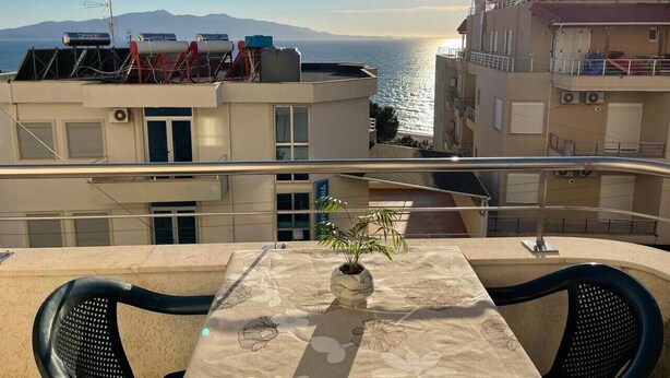 Un balcón con planta en maceta, una mesa y sillas.