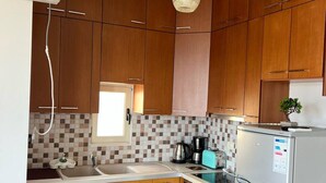 Una cocina con armarios de madera, horno empotrado, refrigerador y ventana.