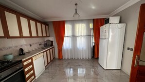A kitchen with a stove, sink, cabinets, and a refrigerator.