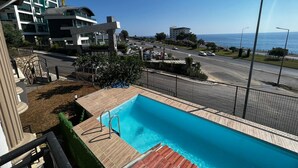 A swimming pool with a view of the sea and a road.