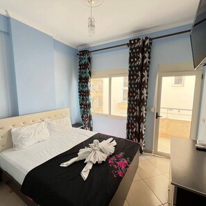 Une chambre d’hôtel avec un lit, une télévision, un balcon avec des rideaux et une vue sur l’extérieur.