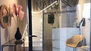 A boutique apartment with a reception desk, a modern chair, and decorative elements like a vase with pampas grass. - Narciso Boutique Apartment - room n3 (Acireale)