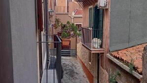 A narrow alleyway between buildings with a small balcony, a potted plant, and a tiled roof. - Narciso Boutique Apartment - room n3 (Acireale)