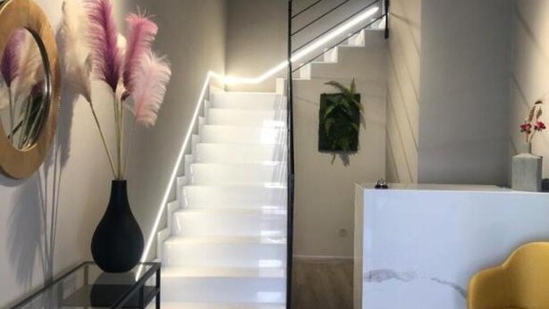 Ein modernes Interieur mit einer Treppe, einer schwarzen Vase mit Blumen und einem gelben Sessel.