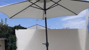 Una veranda con tavolo, due sedie e un ombrellone grande.