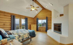 Ein Schlafzimmer in einer Blockhütte mit Bett, Kommode und Kamin.