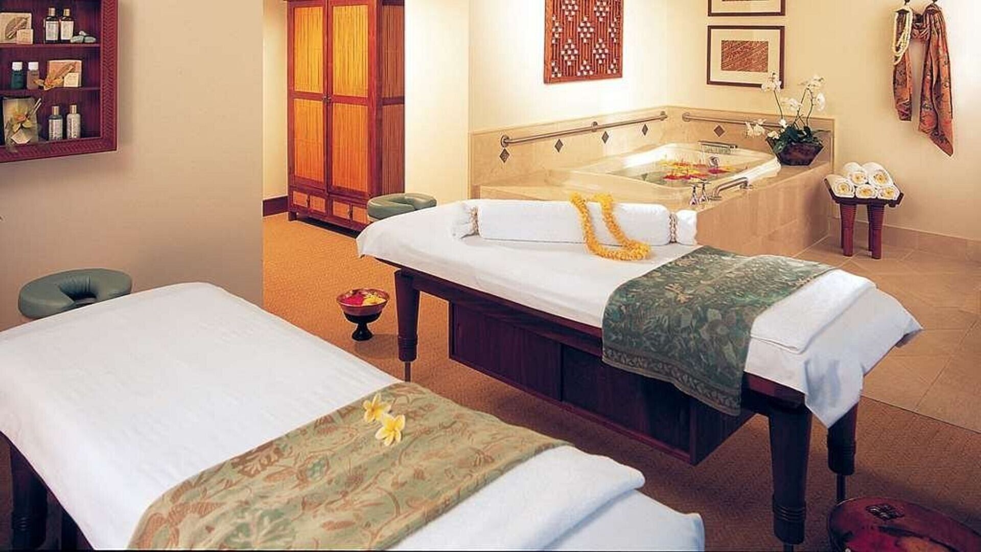 A spa room with a massage table, a separate bathtub, and a small sink.