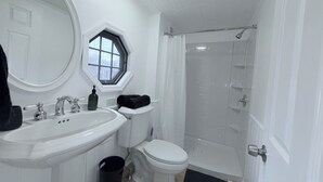 A bathroom with a white sink, toilet, and shower.