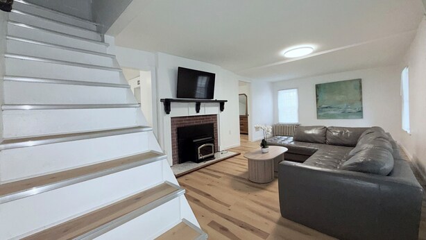 A modern living room with a fireplace, a sofa, a TV, and a staircase.