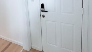 A white door with a keyhole and a handle, a white wall, and a wooden floor.