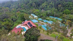 Ein Resort mit mehreren Gebäuden, einem Schwimmbad und üppiger Waldlandschaft.