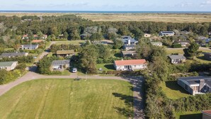 Luchtbeeld van een woonwijk met huizen, gazons en een verre kustlijn.