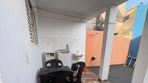 Un pequeño patio con una mesa, sillas, un lavamanos y piso de baldosas.