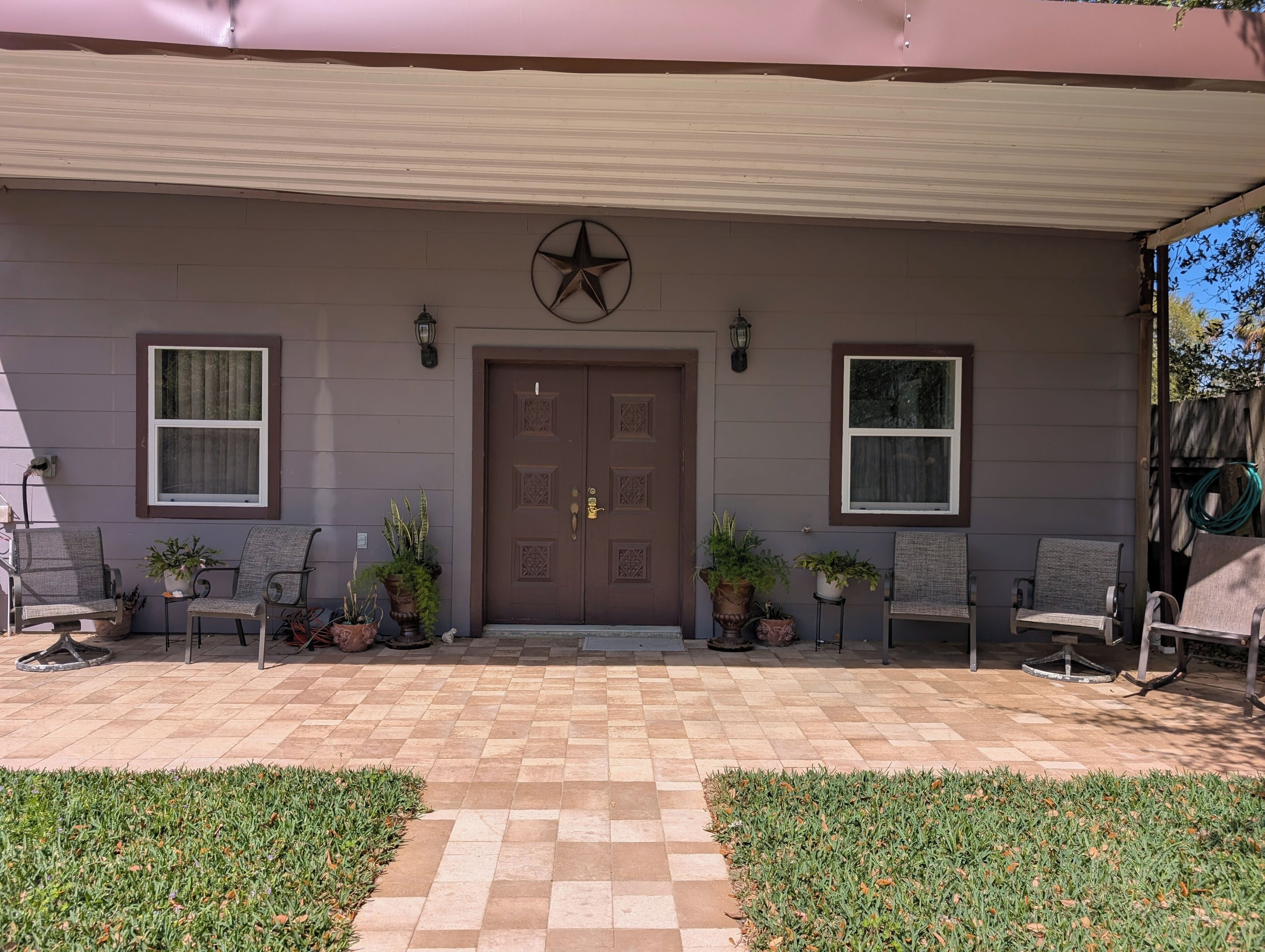 A house with a checkered patio, a brown door, and potted plants.