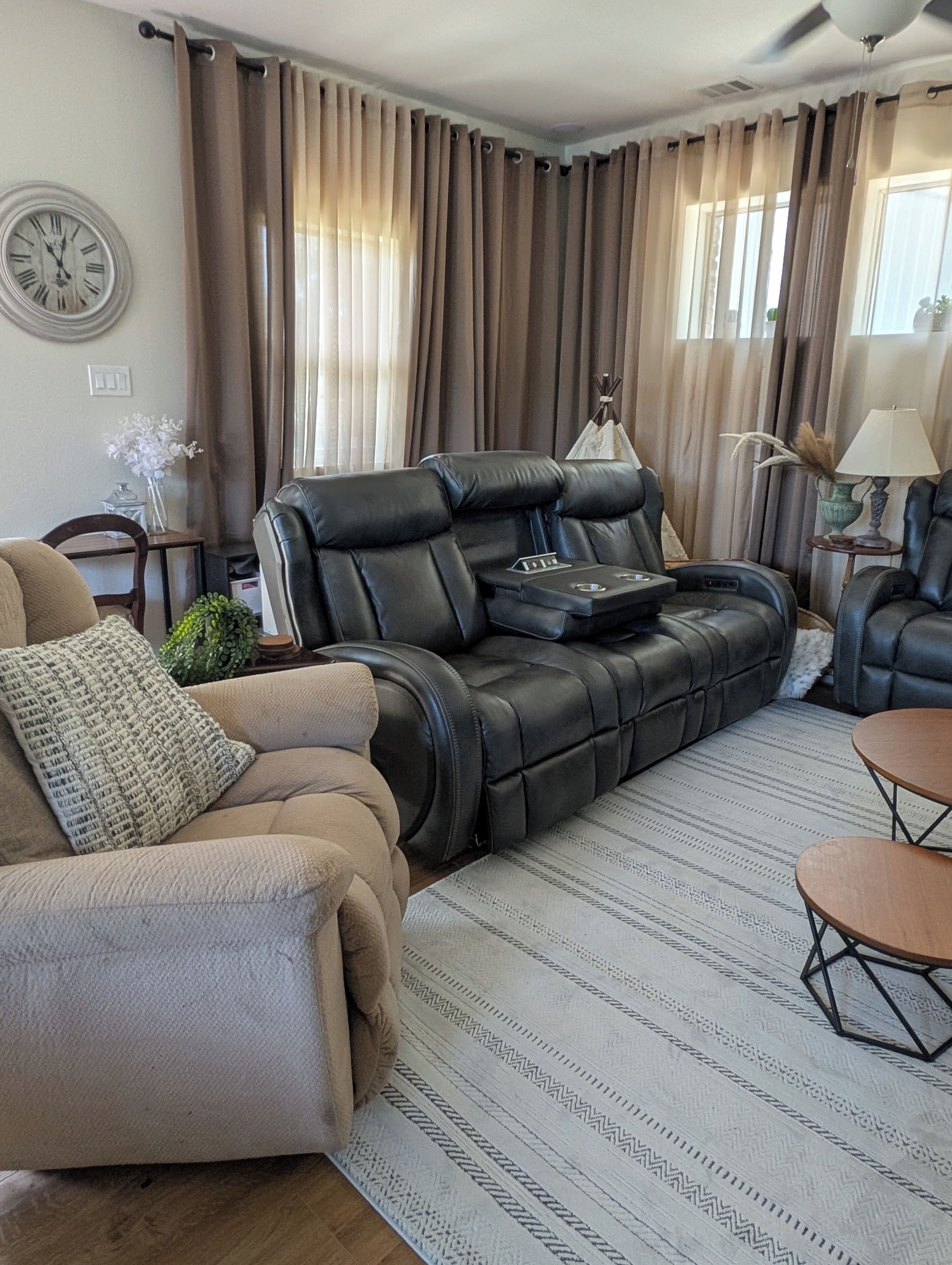A living room with a leather sofa, a coffee table, a lamp, and a clock on the wall.
