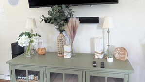 A green cabinet with glass doors, a flat-screen TV mounted above, and various decorative items on the cabinet.