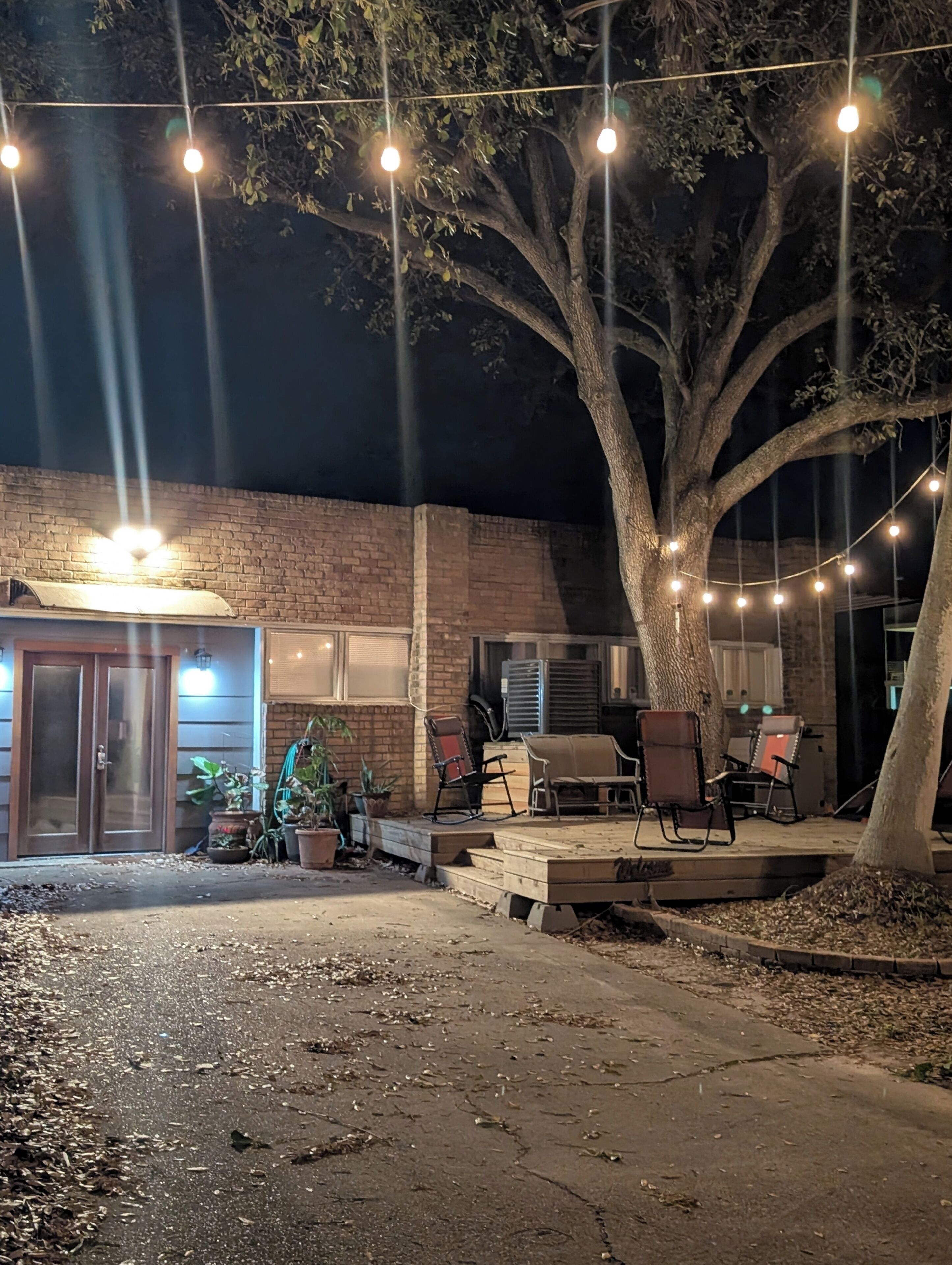 An outdoor patio area with string lights, a brick building, and outdoor furniture.