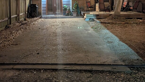 A backyard with a brick building, string lights, a tree, and outdoor furniture.