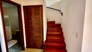 A staircase with red steps leading to a landing, a wooden door, and a tiled floor. - Villa 9B Toucan Valley Jungle Village Resort (Ciudad Cortés)