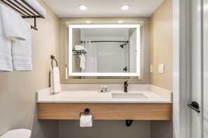 Een moderne badkamer met een grote spiegel, een wastafel en een handdoekrek.