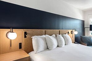 Een hotelkamer met een bed, nachtlampjes, een nachtkastje en een stoel.