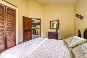 Ein Schlafzimmer mit einem Bett, einem Schminktisch, einem Spiegel und einer Tür zum Küchenbereich.