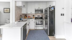 A modern kitchen with white cabinetry, stainless steel appliances, a microwave, oven, and refrigerator.