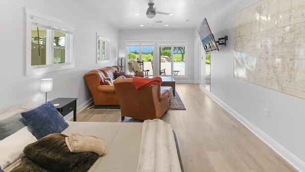 A spacious living room with a sofa, armchair, and a flat-screen TV mounted on the wall.