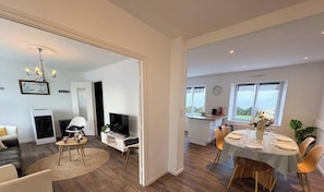 A modern living room with a TV, seating, and a chandelier. - Ty Castel - Family home near the sea (Saint-Pabu)