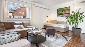 Een moderne woonkamer met een bank, fauteuil, salontafel en een potplant.