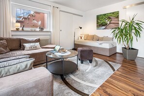 A modern living room with a sofa, armchair, coffee table, and a potted plant. - Apartment 'Ferienglück Vogelsang' with Private Terrace, Garden, and Wi-Fi (Loßburg)