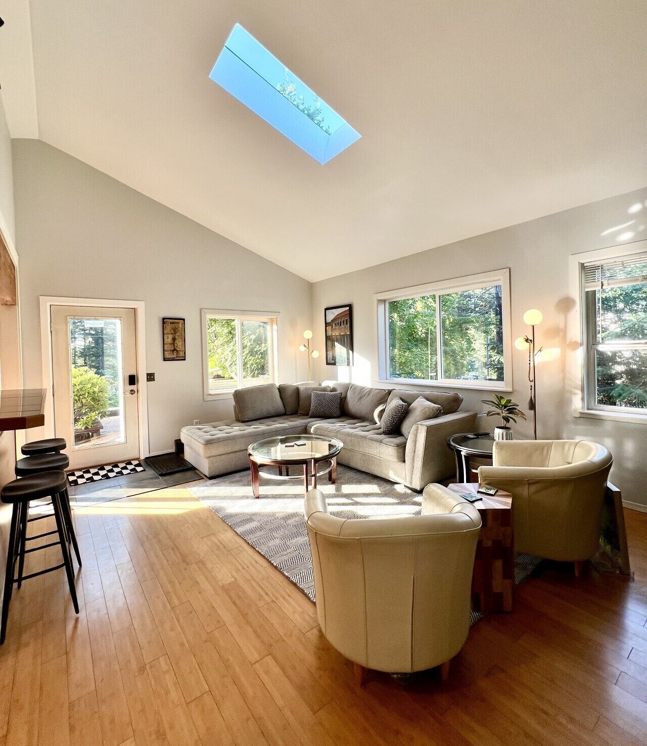 A spacious living room with a large sectional sofa, a round coffee table, and a glass-top dining table.