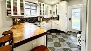 A kitchen with a central island, white cabinets, and patterned flooring. - THE HIDE AWAY | 1 Bedroom King Suite (Kodiak)